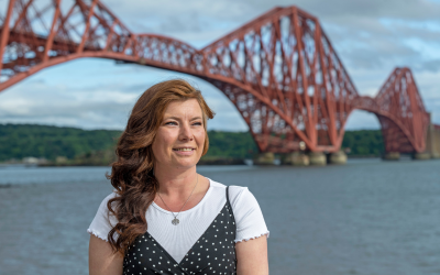 OU student Carol Hunter sitting in front of the Forth Road Bridge